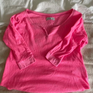 Rosa ribbad tröja från Hollister - Superfin rosa tröja från Hollister i ribbad bomull med trekvartsärm och v-ringad hals med liten slits. Perfekt för dig som gillar färg och vill ha en bekväm och snygg basic i garderoben.