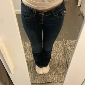 Mörkblå jeans med raka ben - Snygga mörkblå jeans med raka ben och klassiska kontrastsömmar. Byxorna har låg midja och coola fickdetaljer med knapp bak. Perfekta för dig som gillar en tidlös och enkel stil. Materialet är jeans med en skön passform.