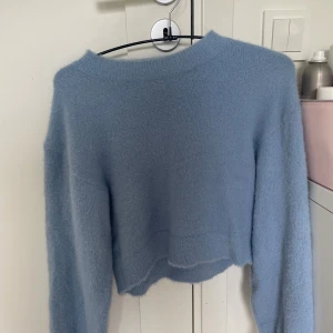 Ljusblå croppad stickad tröja XS - Supermjuk och fluffig ljusblå stickad tröja från Divided. Modellen är croppad med lång ärm och har en enkel, avslappnad passform. Perfekt att slänga på sig för en chill look. Snygg till både jeans och kjol!