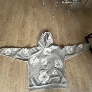 Denim tears hoodie.  - Grå hoodie från Denim Tears i storlek S, tillverkad i 100% bomull. Tröjan har vita blommiga tryck över hela framsidan. Riktigt fet, och stilren. Passar sjukt fint inför sommaren. Äkthet kan tyvärr inte garanteras, därav priset!! Passar M/L! Kan mötas upp i Skåne!
