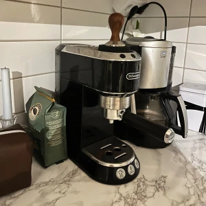 DeLonghi Espressomaskin - Snygg och kompakt DeLonghi espressomaskin i svart och krom. Utrustad med portafilter och trä-tamper. Maskinen ser välvårdad ut med minimalt slitage, perfekt för dig som vill göra espresso hemma. Enkel att använda med tydliga knappar för olika funktioner. Nypris ca 1799