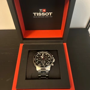 Tissot Seastar svart kronografklocka - Säljer en Tissot Seastar kronograf med svart urtavla och silverfärgad länk i rostfritt stål. Klockan har tydliga index, vridbar bezel och flera små urtavlor för tidtagning. Snygg och sportig design med robust känsla. Levereras i originalask.