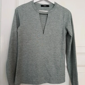 Grå långärmad tröja från Bik Bok - Snygg grå långärmad tröja från Bik Bok med en djup v-ringning framtill. Tröjan har en enkel och stilren design i mjukt material, perfekt för lager-på-lager. Passar till både jeans och kjol för en chill look.
