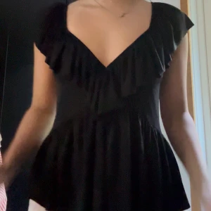 Svart volangklänning med öppen rygg - Supersöt svart topp med volanger från zara. Säljs ej längre. Stl s/m. Stretchigt material