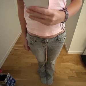 Lågmidjade jeans från Gina Tricot - Säljer ett par grå jeans från Gina Tricot i storlek 152. Jeansen har låg midja, raka ben och klassisk femficksdesign. De är tillverkade i mjukt denimtyg och har dubbla knappar framtill för en snygg detalj.