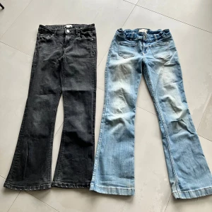 Bootcut jeans Gina Tricot & Abercrombie - Två par bootcut jeans: ett par svarta från Gina Tricot i storlek 152 och ett par ljusblå från Abercrombie i storlek 15/16 short. Båda har klassisk femficksdesign, dragkedja och knapp, tillverkade i jeansmaterial. Snygga och trendiga med utsvängda ben.