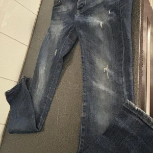 Dolce & Gabbana blå jeans slim. - Snygga blå jeans från Dolce & Gabbana med slitna detaljer. Jeansen har klassisk femficksdesign, orangea sömmar och metallknapp med logga. Tillverkade i kraftigt jeanstyg som ger en cool och tidlös look. Köpt för 5000kr säljer för 3000krr pris kan diskuteras lägre. Skriv gärna till mig först innan ni vill köpa!