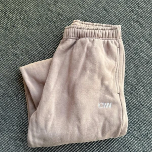 Beige mjukisbyxor från ICANIWILL - Beiga mjukisbyxor från ICANIWILL med broderad vit logga på benet. Perfekt till träning eller hemma. Storlek M