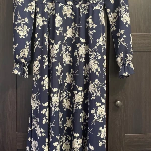 Marinblå Shein klänning - Säljer en superfin marinblå, blommig vardagsklänning från Shein. Klänningen har en markerad midja med knytband och volangdetaljer vid ärmsluten, samt en luftig passform.