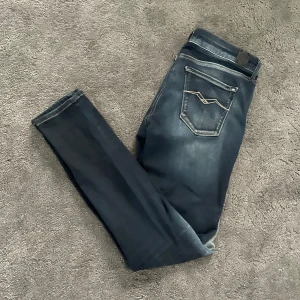 Replay Jeans - Snygga mörkblå Replay jeans med slim passform och modernt broderi på bakfickan. Jeansen har klassisk femficksdesign och en snygg wash för en trendig look. Perfekta för dig som vill vara stilig men ändå bekväm i din vardag.