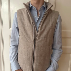 John Henric Väst Beige - Denna John Henric väst är perfekt för dig som vill värma dig lite extra nu i höst med ett unikt och formellt plagg. I kombination med en overshirt kan denna även användas på vintern för dig som ogillar tjocka jackor. Köpt för 1500 på hemsidan och har använts mycket sparsamt. Västen har inga defekter alls! Säljs nu för 600kr men priser kan självklart diskuteras.
