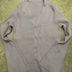 Ljuslila ribbad kofta med knappar - Säljer en ljuslila ribbad kofta med v-ringning och knäppning framtill. Koftan har långa ärmar och är tillverkad i ett mjukt stickat material. Storlek S (36), stor i storlek funkar även för en M, tjockt och bra material, för stor på mig därför ska sälja den. 