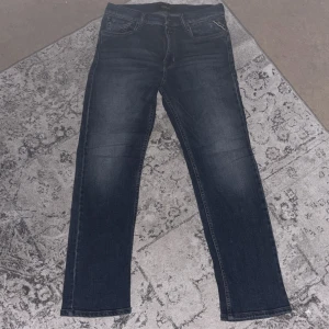 Replay mörkblå jeans straight fit - Snygga mörkblå jeans från Replay med klassisk femficksdesign och raka ben. Jeansen har diskreta slitningar framtill och logotypdetalj på fickan. Passar dig som gillar en enkel och stilren look. Materialet är mjukt jeans-tyg med bra stretch.