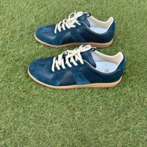 Maison Margiela sneakers - Maison Margiela sneakers i marinblå mocka och skinn med vita snören och beige sula. Klassisk low-top modell med rund tå och snygga paneler i både mocka och skinn. Perfekta för dig som gillar stilrena och exklusiva sneakers med unik design. Storlek 42 man, väldigt bra skick 9 av 10, Box och dustbag medföljer, pris 2999kr men kan gå ner lite vid snabb affär😁.