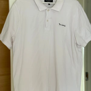 Vit pikétröja från Bondelid XL - Vit pikétröja från Bondelid i klassisk stil med krage och två knappar framtill. Diskret Bondelid-logga broderad på bröstet. Tillverkad i mjuk bomull som är skön mot huden. Kortärmad och med normal passform, perfekt för en clean och enkel look. NYPRIS: 399kr