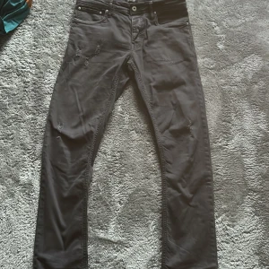 Svarta jeans från Jack & Jones - Svarta jeans från Jack & Jones med slitna detaljer på låret och klassisk femficksdesign. Jeansen har raka ben och är tillverkade i ett mjukt bomullsmaterial. Perfekta för dig som gillar en avslappnad och stilren look.