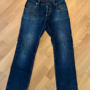 Mörkblå jeans från Armani - Snygga mörkblå jeans från Armani med klassisk femficksdesign och diskret logga på bakfickan. Jeansen har raka ben och normal passform, tillverkade i slitstarkt denimtyg. Perfekta för dig som gillar stilrena och tidlösa jeans.