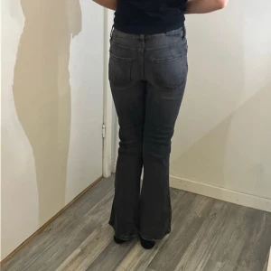 Mörkgrå bootcut jeans - Snygga mörkgrå jeans med bootcut-modell och klassisk femficksdesign. Jeansen har en något utsvängd passform nertill och normal midja. Perfekta för dig som gillar en retrovibe och vill ha ett par jeans som sticker ut lite extra.