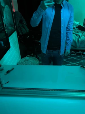 Blå skjorta Polo Ralph Lauren slim fit - Säljer en klassisk blå skjorta från Polo Ralph Lauren i slim fit-modell. Skjortan har långa ärmar, knappar framtill och den ikoniska broderade loggan på bröstet. Tillverkad i bomull för en skön och stilren känsla. 