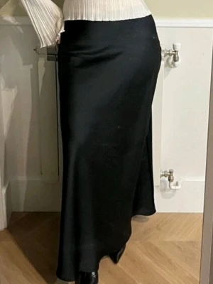 Svart Shein satin långkjol  - Supersnygg Shein svart långkjol med glansig satin-feeling och elastisk midja. Storlek XL eller 44. Resår i midjan, så den funkar för 42 eller 44 Kjolen har en mjuk och följsam passform som ger en clean och stilren look. Perfekt att styla med boots eller sneakers för en trendig vibe. Aldrig använd.