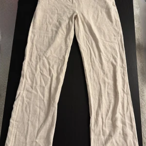 Beiga linnebyxor från Nelly - Säljer ett par beiga linnebyxor från Nelly med raka ben och hög midja. Byxorna har bälteshällor, sidofickor fram och fuskfickor bak. Nya med prislapp kvar 