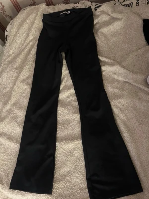 Svarta bootcut leggings - Säljer ett par svarta leggings med bootcut-modell. De har medel hög midja och är gjorda i ett stretchigt material som sitter skönt på kroppen. Perfekta för dig som gillar en enkel men trendig look.