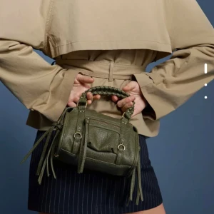 Olivgrön handväska med flätat handtag - Säljer min olivgröna handväska från berhska i skinmatrial p.g.a att jag aldrig använder den. Skicket är exakt som en ny och den är använd ich 3-5 gånger❤️❤️❤️❤️+pris går självklart att diskutera❤️❤️