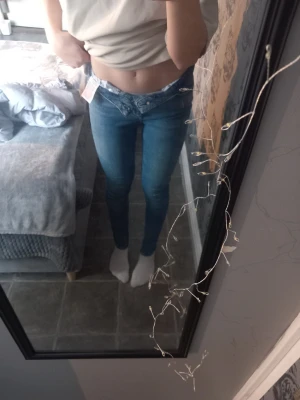 Blå slim jeans från Vero Moda M/32 - Säljer ett par blå slim fit jeans från Vero Moda i storlek M/32. Modellen är midwaist och har klassisk femficksdesign med dragkedjegylf. Jeansen är i stretchigt denimtyg som sitter tajt längs benen och ger en snygg siluett.