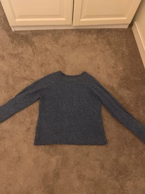 Blå stickad tröja från Vero Moda - Mysig blåmelerad stickad tröja från Vero Moda i storlek XS. Tröjan har rund halsringning och långa ärmar, perfekt för kyliga dagar. Enkel och stilren design som passar till allt!🥰