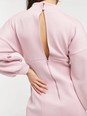 Ljusrosa kort klänning med ballongärm - Supersöt ljusrosa kort klänning med ballongärmar och hög hals. Klänningen har öppen rygg med knappdetaljer och dragkedja bak. Materialet är slätt och känns mjukt mot huden.Perfekt för vintern! Helt ny! Använd bara en gång! 