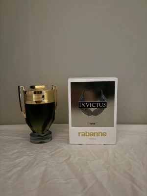 Invictus Parfum av Rabanne - Upptäck Invictus Parfum från Rabanne – en ikonisk doft i en unik troféformad flaska. Perfekt för dig som vill sticka ut och addera en exklusiv touch till din stil. Parfymen levereras i originalförpackning.