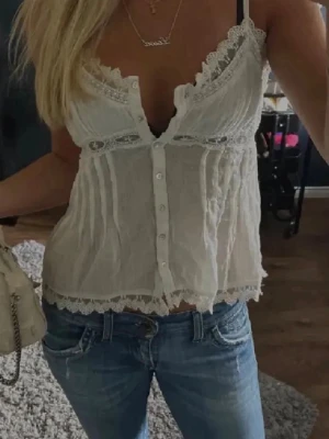 Vit spets topp från Zara - Supersöt vit linnetopp med tunna axelband och knappar framtill.  Toppen har spetskant vid urringningen och nederkanten. Passar perfekt till sommaren, tröjan är i bra skick men passar tyvärr inte mig!💓💓😌🙏😘