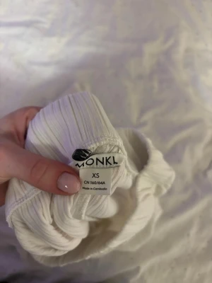 Vit ribbad väst från Monki XS - Säljer en vit väst från Monki i storlek XS. Västen har ett ribbat tyg som ger en snygg struktur och är gjord i ett mjukt, stretchigt material. Enkel och clean design som passar till många olika outfits.