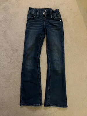 Mörkblå bootcut jeans med detaljer - Säljer ett par justerbara mörkblåa jeans med bootcut passform ifrån Gina tricot young i storlek 146❤️ broderi på fickorna, du får betala frakten! nypris: 359kr OBS! Jeansen saknar en knapp på backfickan, men det orsakar ingen missfunktion❤️