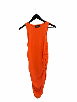Orange ribbad klänning från Cider - Snygg orange ribbad klänning från Cider med ärmlös design och draperad detalj på sidan. Klänningen har en kroppsnära passform. Helt oanvänd. Du betalar själv för frakten 💕