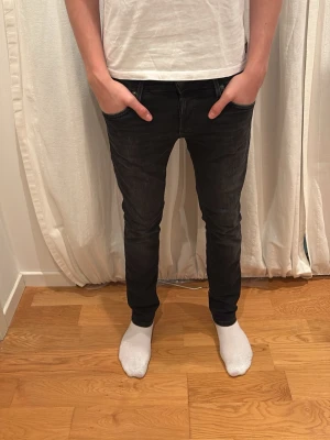 Svarta slim jeans - Säljer ett par svarta slim jeans med klassisk femficksdesign och smal passform. Jeansen har låg midja och är tillverkade i stretchigt jeansmaterial för en bekväm känsla. Perfekta till sneakers eller boots. Jack&Jones 27/30
