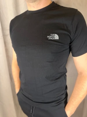 Svart t-shirt från The North Face - Snygg svart t-shirt från The North Face med klassisk logga tryckt på bröstet. Modellen är enkel och stilren med rund hals och korta ärmar. Tillverkad i mjuk bomull som känns skön mot huden. Perfekt till jeans eller shorts.