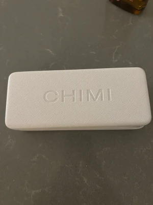 Beige CHIMI solglasögon med etui - Säljer ett par snygga solglasögon från CHIMI med fyrkantig form och transparent beige båge. Kommer med originalvitt hårt etui och en vit tygpåse. Perfekta för soliga dagar och ger en cool vibe till din outfit.