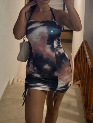 Kort batikmönstrad klänning med snörning - Säljer en kort klänning med tunna axelband och batikmönster. Klänningen har snörning i sidorna som ger en snygg detalj och gör att du kan justera längden. Materialet är mjukt och stretchigt och kramar hela kroppen.