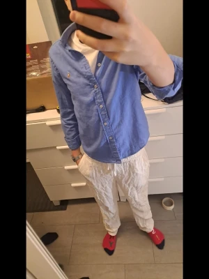 Blå linneskjorta från Ralph Lauren xs - Säljer en klassisk blå skjorta från Ralph Lauren i mjukt linne. Skjortan har lång ärm, knappar framtill och den ikoniska broderade loggan på bröstet. Perfekt till jeans eller chinos för en clean och stilren look. 