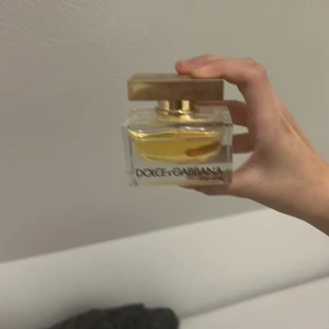 Parfym Dolce & Gabbana The One - Säljer en elegant parfym från Dolce & Gabbana, The One. Flaskan är rektangulär med en gyllene kork och innehåller en gyllene vätska. Perfekt för den som vill ha en lyxig doftupplevelse.