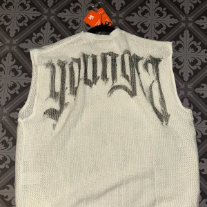 Vitt linne från Youngla - Vit cuffed youngla linne. Linnet har en luftig och sportig känsla, perfekt för gymmet men också streetwear. Rund halsringning och avslappnad passform. Säljer pga att den var för stor för mig, perfekt för dem som vill ha ett oversized gym linne med stil.