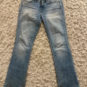 Ljusblå bootcut jeans  - Snygga ljusblå jeans från Pepe jema med bootcut passform och klassisk femficksdesign. Jeansen har slitningar och en cool broderad detalj på bakfickorna. Tillverkade i mjukt denimtyg med lätt tvättad look och råa kanter nertill.