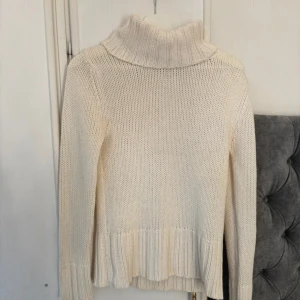 Stickad polotröja - Säljer en stickad polotröja med grov ribbad krage och muddar. Tröjan har lång ärm och är tillverkad i ett mjukt material som känns skönt mot huden. Perfekt för att hålla värmen under kyliga dagar och har en klassisk, enkel look. Är lite nopprig och har några fläckar💓Pris kan diskuteras 💕