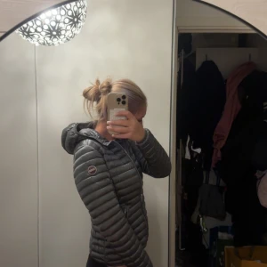 Grå  dunjacka från colmar  - Säljer en snygg mörkgrå dunjacka från colmar i storlek 40/XS. Jackan har en croppad passform, huva och två fickor med dragkedja. Den är quiltad och har colmar märke  på ärmen. Jackan är i nyskick och har inga defekter.