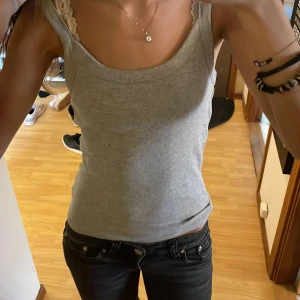 Grå ribbad linnetopp Gina Tricot - Säljer en ljusgrå ribbad linnetopp från Gina Tricot, basically basics-kollektionen. Toppen är ärmlös med breda axelband och har en rundad halsringning. Perfekt att styla med jeans eller shorts för en chill look.