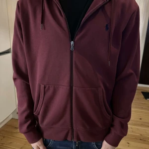 Vinröd hoodie från Polo Ralph Lauren - Säljer en vinröd hoodie från Polo Ralph Lauren med dragkedja, huva. Knappast använd.