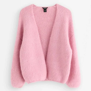 Ljusrosa stickad kofta från Lindex - Supermjuk och fluffig ljusrosa stickad kofta från Lindex. Koftan har en öppen front utan knappar, långärmad design och en loose passform som ger en chill vibe. Perfekt att slänga över en t-shirt för extra mysfaktor.