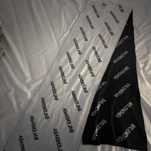 Balenciaga svartvit halsduk med logga - Snygg halsduk från Balenciaga i svart och vitt med tydligt logomönster över hela halsduken. Den är lång och rektangulär, perfekt att vira flera varv. Stilren och trendig accessoar för dig som gillar streetstyle och designerplagg.