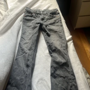 Grå jeans low waist bootcut från Gina  - Säljer ett par grå jeans med bootcut och lowwaist. Jeansen har en snygg tvättad look. Lite sliten vid kanten men inget man tänker på enligt mig. Storlek 158 i Gina Young 